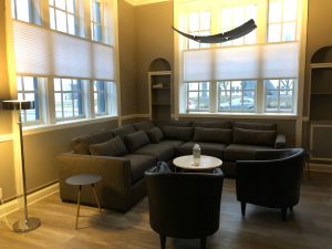 A modern sectional sofa with two armchairs and a small table in a well-lit room.